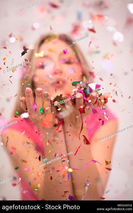 Beautiful woman blowing confetti in the air party new years eve celebration isolated on white background