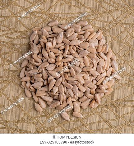 Top view of circle of shelled sunflower seeds against beige vinyl background