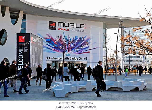 People walk to the entrance of the fair grounds, Fira Gran Via one day before the official opening of the Mobile World Congress in Barcelona, Spain