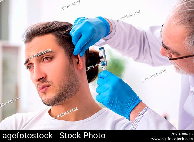 Young man visiting old doctor dermatologist