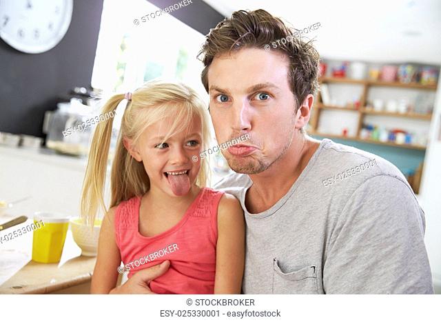 Father And Daughter Making Funny Faces At Breakfast Table