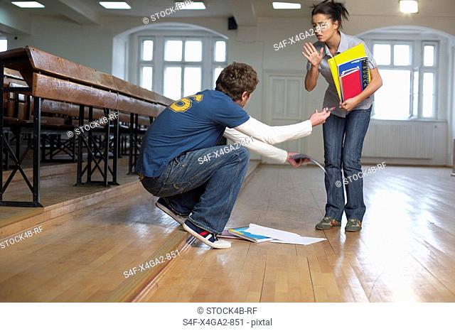 Man picking up the booklets of a young woman in an auditory, low angle view