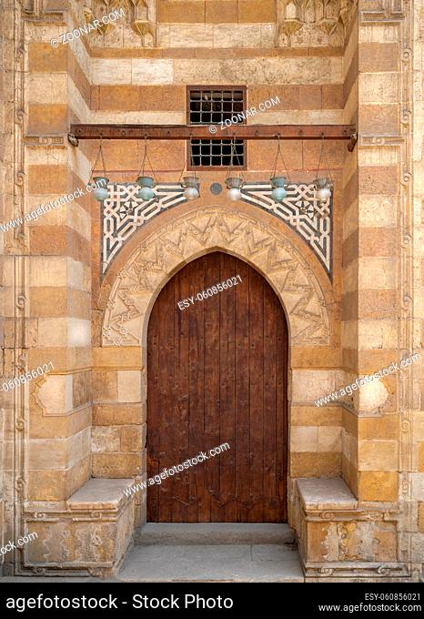 Wooden aged grunge door and stone bricks wall, one of the exterior doors of Aqsunqur Mosque (Blue Mosque) located in Bab El-Wazir District, Medieval Cairo
