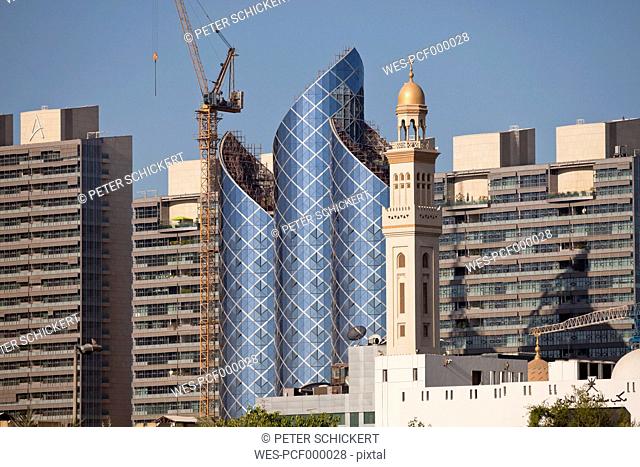 UAE, Dubai, construction site of a skyscraper besides minaret
