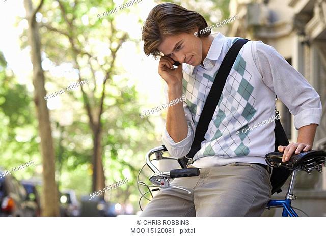 Man sitting on bicycle talking on mobile phone