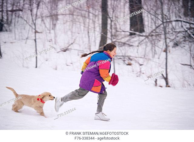 Girl playing with puppy in snow