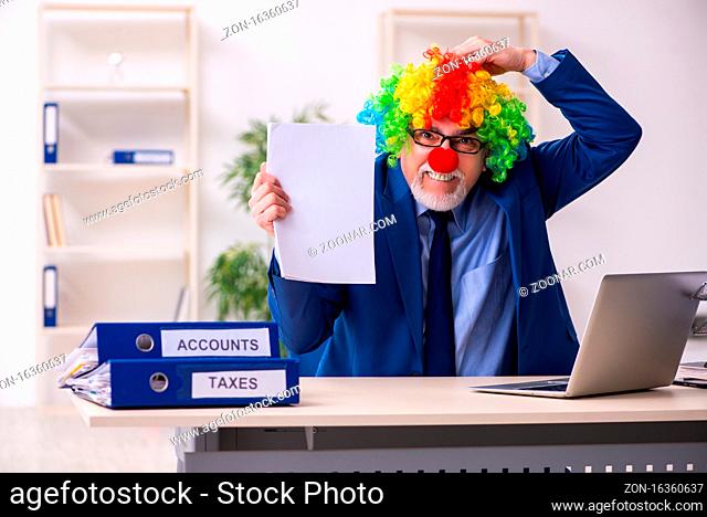 Aged businessman clown working in the office