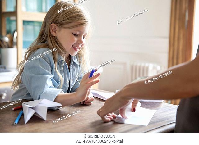 Little girl learning how to make paper airplane