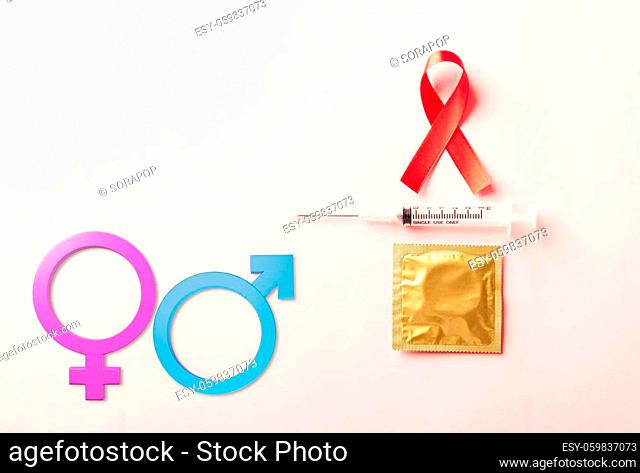 Red bow ribbon symbol HIV, AIDS cancer awareness, condom and syringe with Male, female gender signs, studio shot isolated on pink background