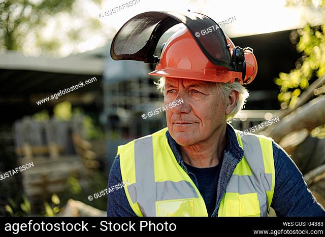 Wrinkled man wearing protective workwear looking away in forest