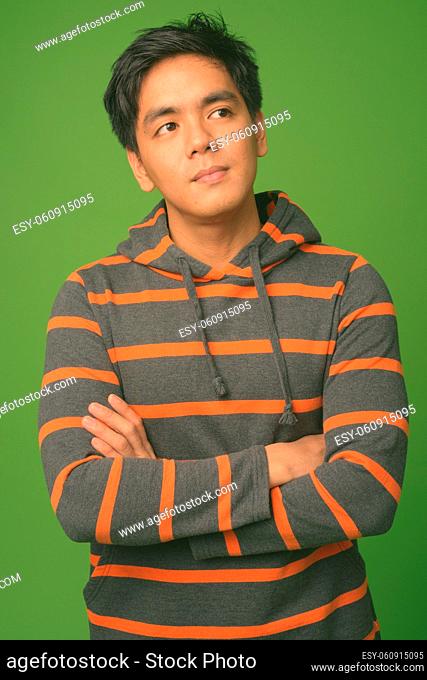 Studio shot of young handsome Filipino man against green background