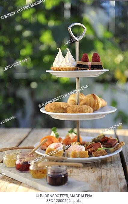 Various canapes and sweet pastries on a cake stand for tea (England)