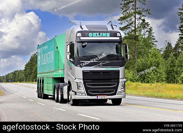 Silver Volvo FH truck of Okline Oy pulls Pilkington glass trailer along Highway 25 on a day of summer. Raasepori, Finland. July 24, 2020