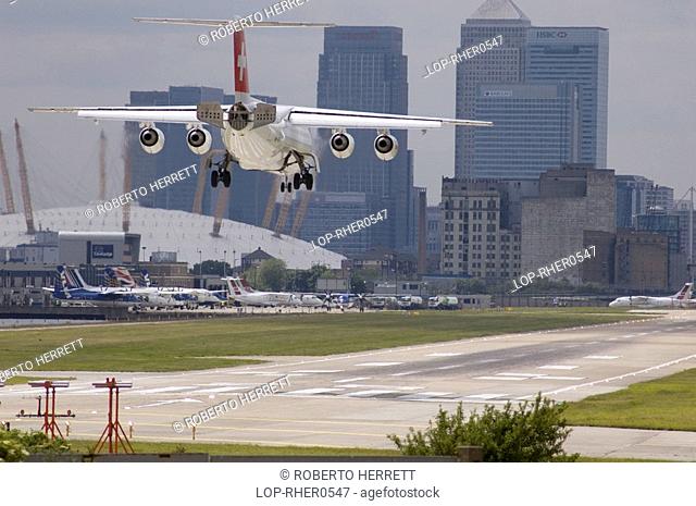 England, London, City Airport, A Swiss Air BAe 146 airplane landing at London City Airport with Docklands and the O2 Arena in the distance