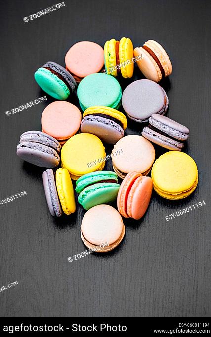 Colorful french macaroons or macarons on black wooden table. Space for text. pastel colors
