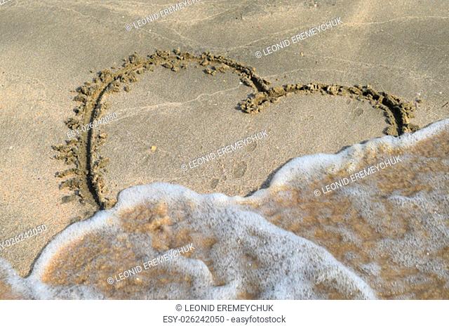 Heart drawn on the beach sand. heart symbol on the sand washed by the sea wave
