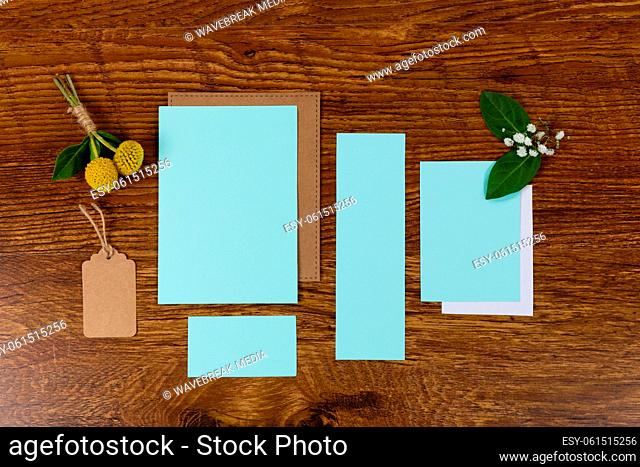 Notebook and blue sheet of papers surrounding by flowers on a wood table