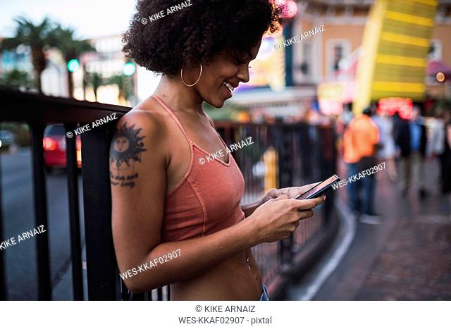 USA, Nevada, Las Vegas, happy young woman using cell phone in the city