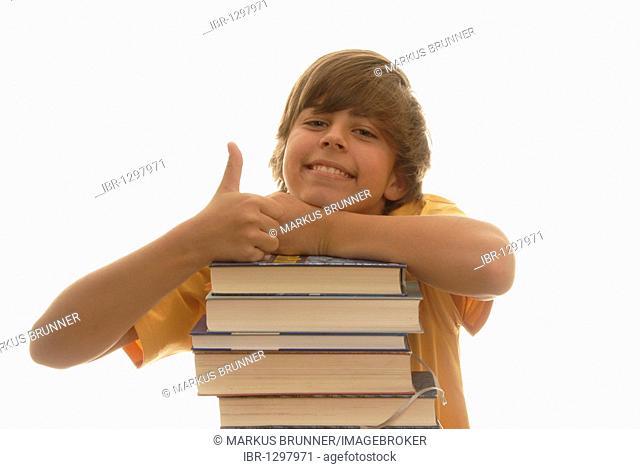 Boy, 16, leaning on a stack of books, looking happy, thumbs up