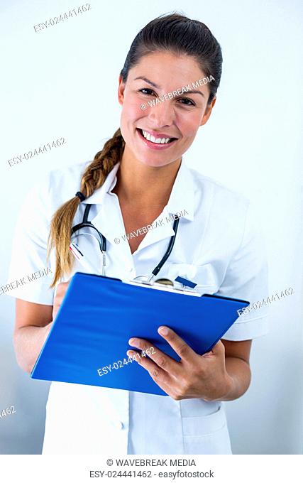 Portrait of female doctor writing on clipboard in hospital