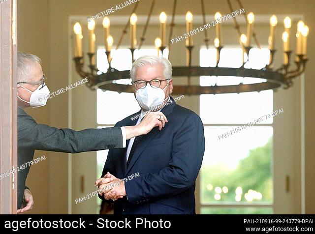 16 September 2021, Berlin: Stephan Steinlein (l), Head of the Office of the Federal President, holds the Federal Cross of Merit on the lapel of Federal...