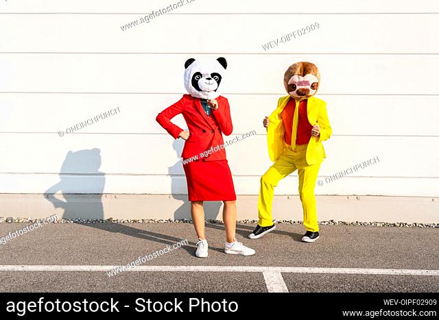 Man and woman wearing animal masks standing in front of wall