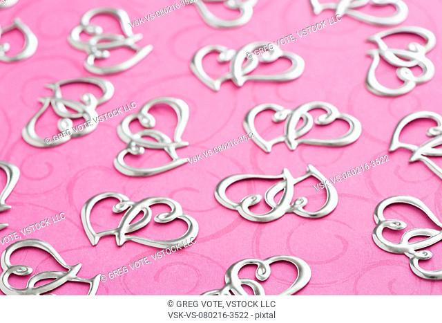 Silver heart shape decorations on pink textile