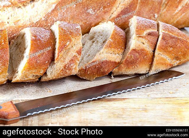 fresh homemade bread, divided into pieces by a knife. photo close-up of food on a cutting board