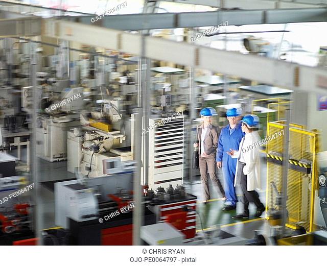 Businesspeople in hard-hats walking on factory floor