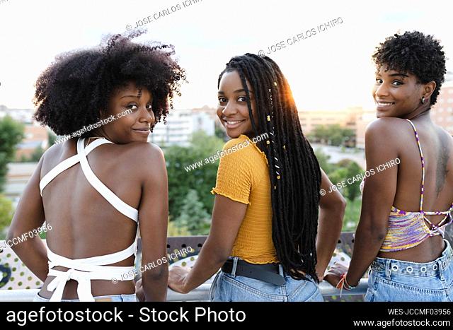 Smiling female friends looking over shoulders
