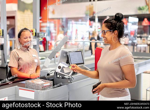 Smiling woman paying at till in supermarket