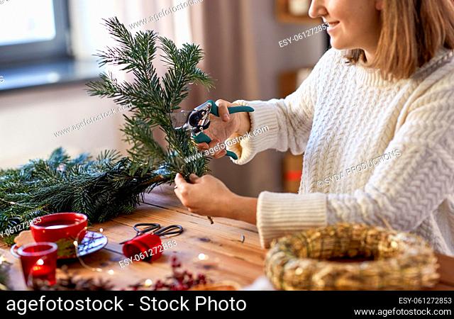 happy woman making fir christmas wreath at home