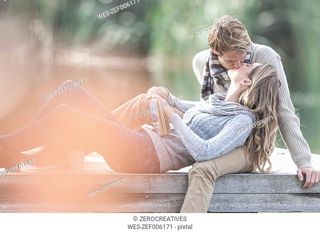 Young couple kissing on a jetty at lake