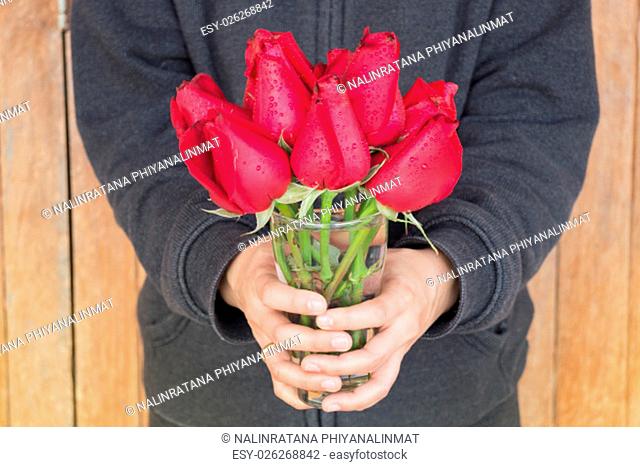 Hand hold glass of red rose, stock photo