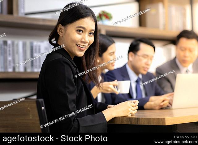Portrait of confidence Businesswoman sit at table in meeting room in cafe with business team in background using for coporate background work