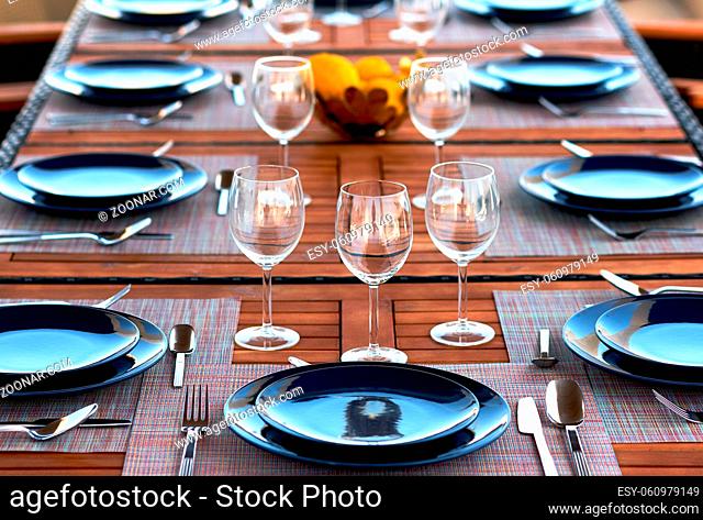 Table setting with empty wine glasses, plates and flatware served on a wooden table. Close up of tableware, dishes, no people