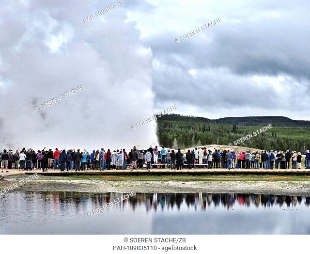 05.07.2018, USA, Canyon Village: Tourists visit the eruption of Old Faithful Geyser in the southwestern part of the park