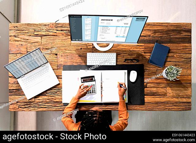 Female Accountant Calculating Tax In Front Of Computer At Desk