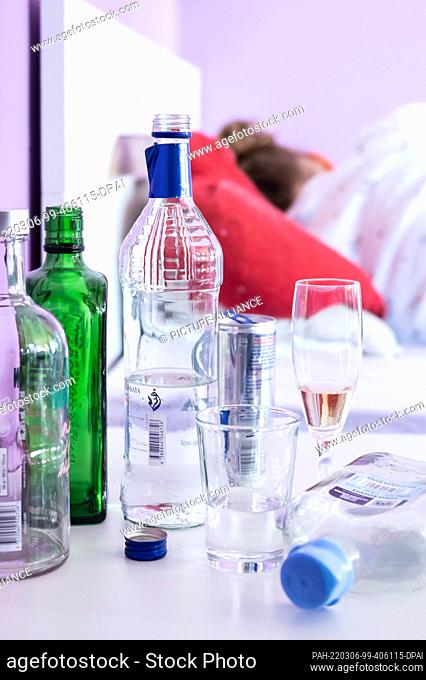 04 March 2022, Baden-Wuerttemberg, Rottweil: Illustration: A teenage girl lies in her bed while bottles of alcohol and glasses are placed on her bedside table