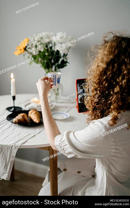 Woman photographing cup through smart phone