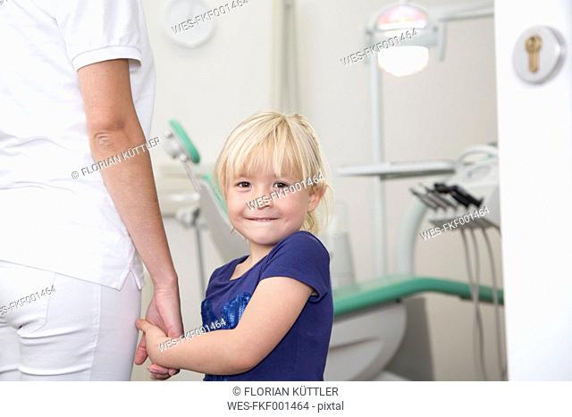 Dental assistant holding girl's hand before treatment