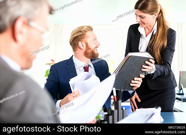 Assistant brings ring binder to meeting of managers