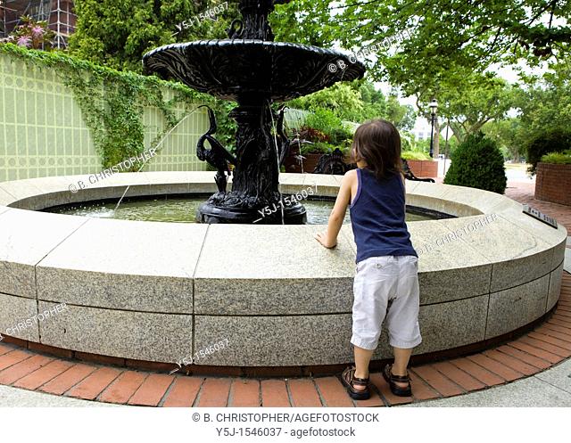 Small child leans on a water fountain to get a better look