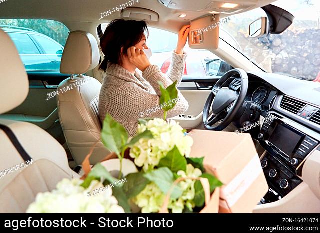 Auto Fahrerin mit Mundschutz und Paketen im Innenraum macht Anruf als Bringdienst Konzept