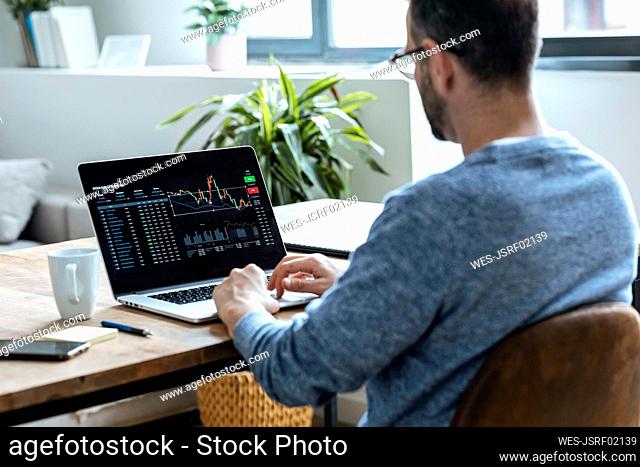 Businessman analyzing stock data on laptop at home