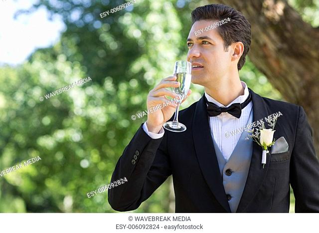 Thoughtful groom drinking champagne