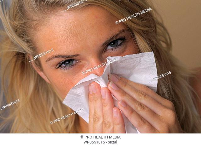 sneezing young woman with a tissue