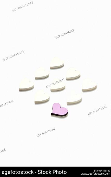Valentine's decorative diagonal pattern from handmade paper white hearts and one of them is pink on a light grey background with soft shadows, copy space