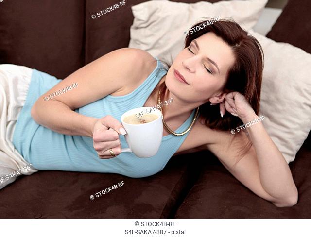 Woman enjoying cup of coffee on couch