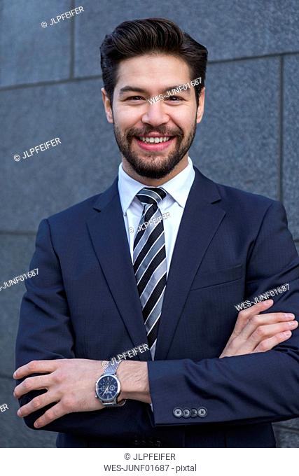 Portrait of bearded young businessman wearing blue suit jacket, tie and wrist watch